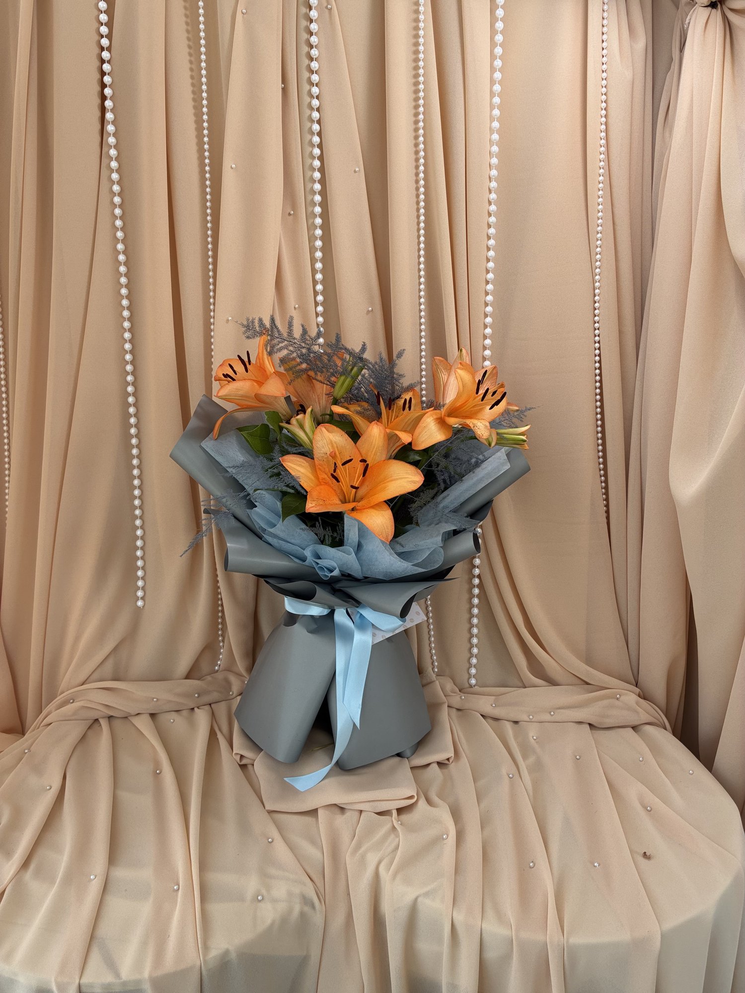 Sunset Flame – Buchet Elegant cu Crini Portocalii și Asparagus Gri